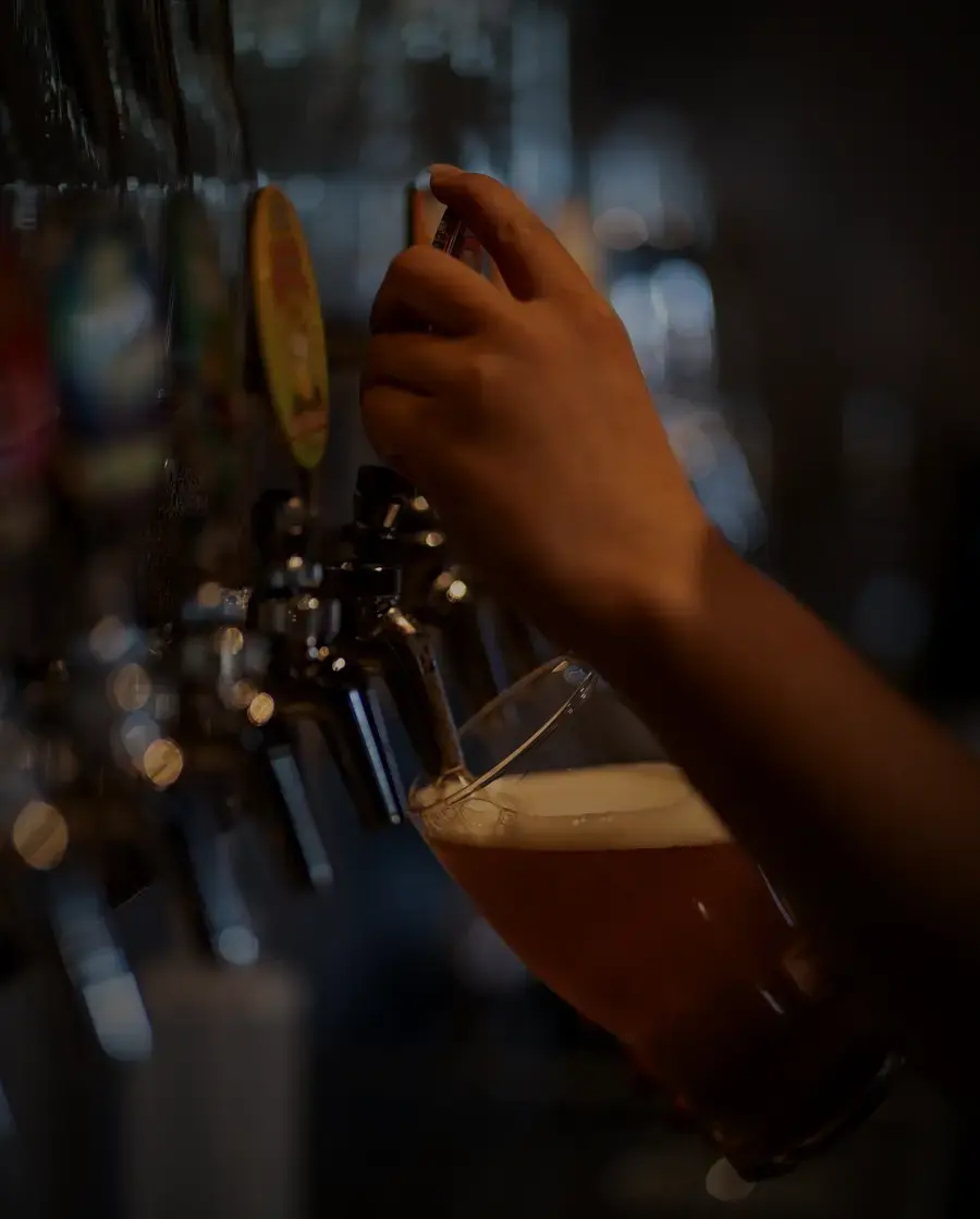 A glass of lager held in front of a bar tap — Tuborg Gold, delivered across Kathmandu Valley by Raksi Hour.