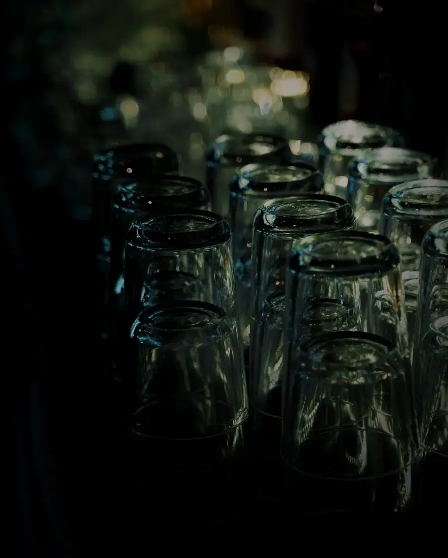 Empty spirit glasses on a dark bar counter — Highlander vodka, delivered across Kathmandu Valley by Raksi Hour.